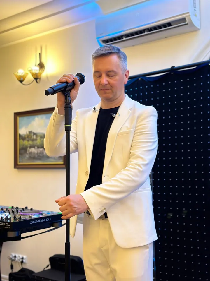 Wokalista Maxis śpiewa przy mikrofonie na tle kurtyny LED